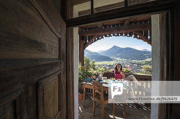 Österreich  Salzburger Land  Altenmarkt-Zauchense  Frau beim Frühstück auf der Veranda des alten Bauernhauses
