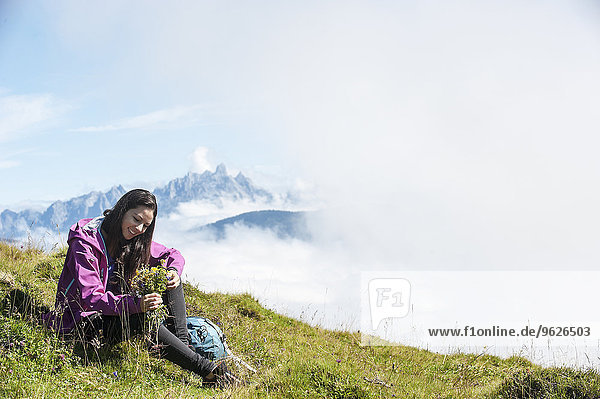 Austria  Altenmarkt-Zauchensee  young woman sitting on alpine meadow