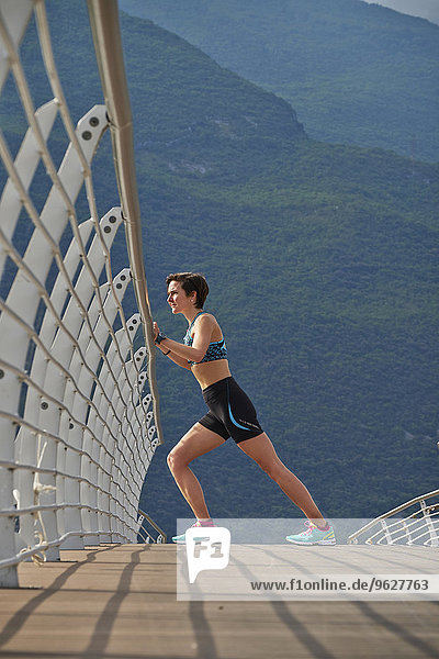 Italy  Trentino  woman stretching on bridge at Lake Garda