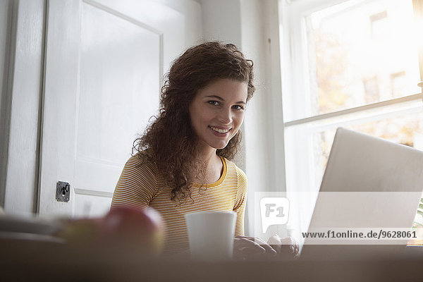 Lächelnde junge Frau zu Hause mit Laptop
