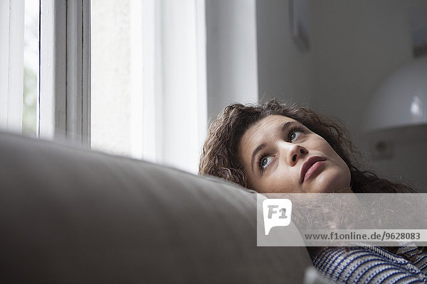 Junge Frau zu Hause mit Blick aus dem Fenster