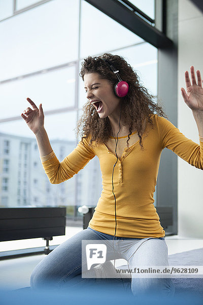 Screaming young woman wearing headphones at the window