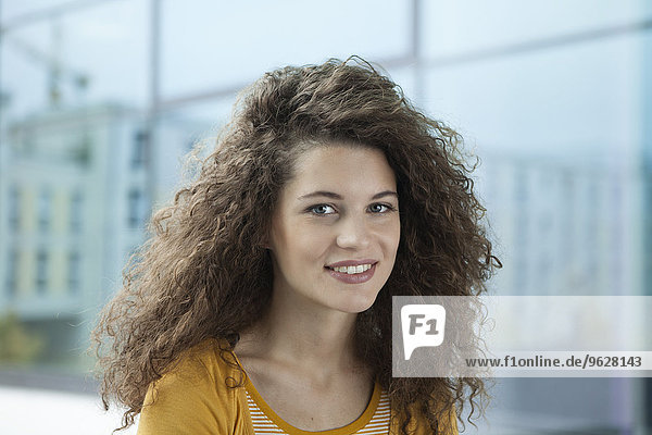 Porträt einer lächelnden jungen Frau am Fenster