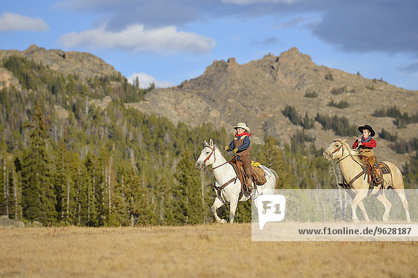USA  Wyoming  two young cowboys riding