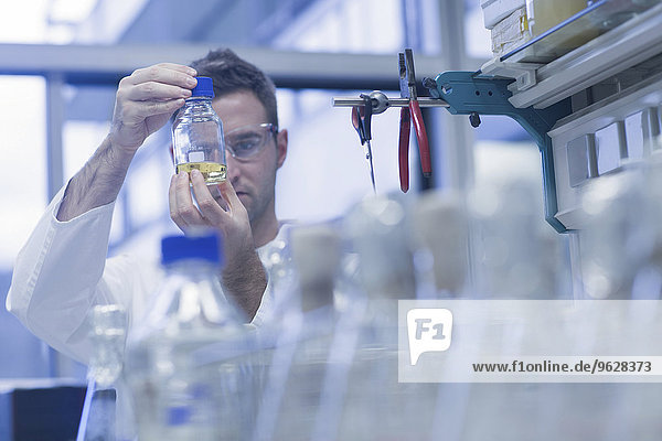 Wissenschaftler im mikrobiologischen Labor mit Blick auf Flüssigkeit in der Flasche