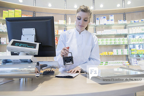 Young pharmacist in pharmacy stamping prescription