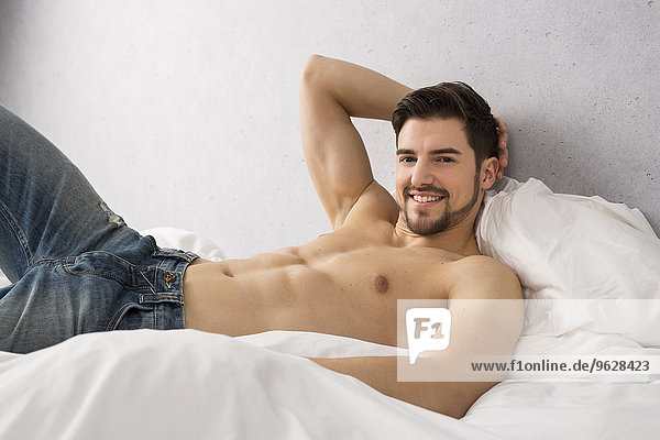 Portrait of shirtless man lying on bed
