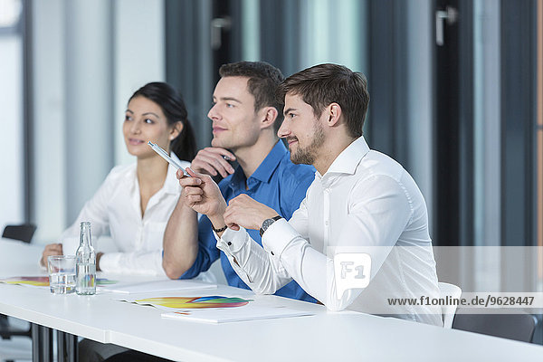 Drei Geschäftsleute  die in einem Konferenzraum zuhören