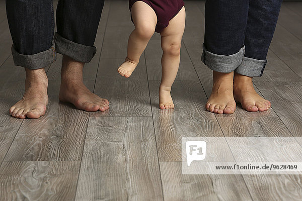 Father  mother and baby girl standing barefoot on floor