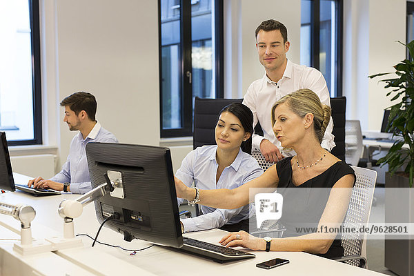 Businesspeople at desk looking at computer monitor