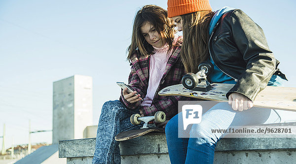 Zwei Mädchen im Skatepark teilen sich das Handy