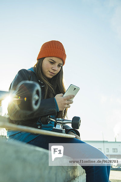 Teenager Mädchen mit Handy im Skatepark
