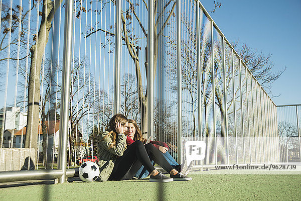Zwei Teenager-Mädchen auf dem Sportplatz teilen sich das Handy