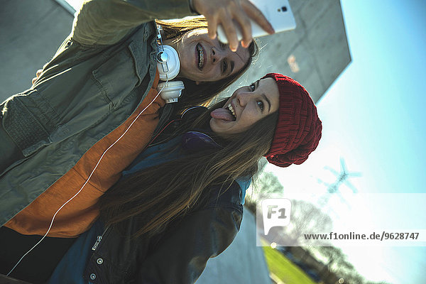 Zwei verspielte Teenagermädchen im Freien  die Selfie nehmen