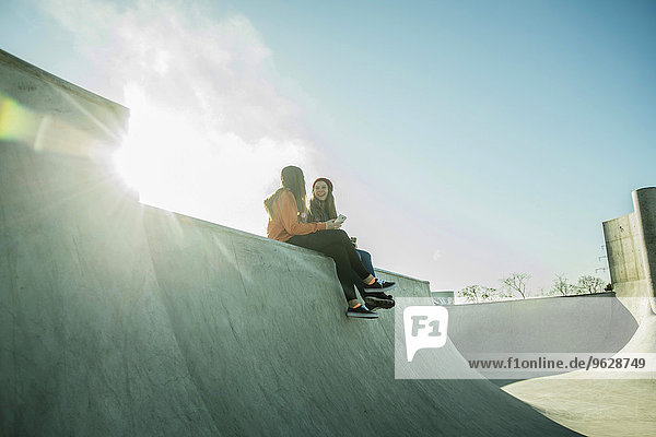 Zwei Teenager-Mädchen im Skatepark teilen sich Handy