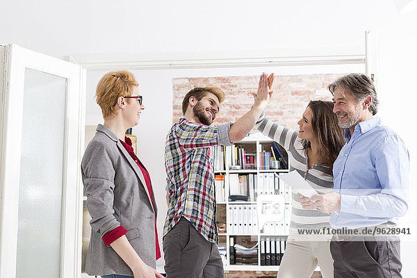 Happy businesspeople high fiving in office