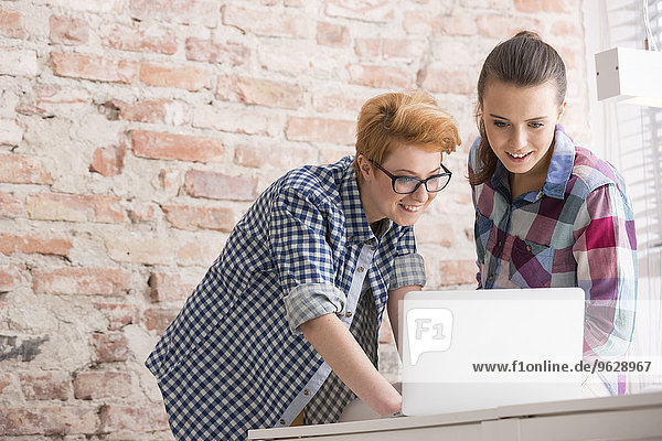 Two young women in office working at laptop