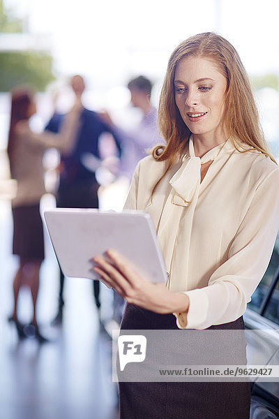 Frau mit digitalem Tablett im Autohaus