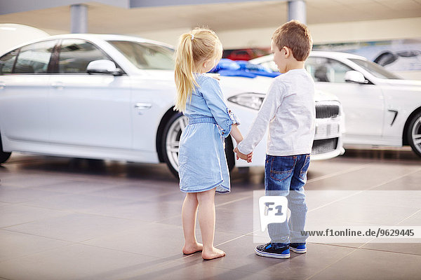 Junge und Mädchen beim Autohändler beim Betrachten des Autos