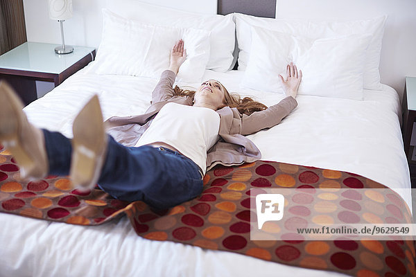 Happy woman falling backwards on hotel bed