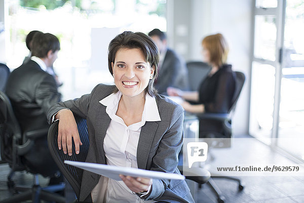 Smiling businesswoman with meeting in the background