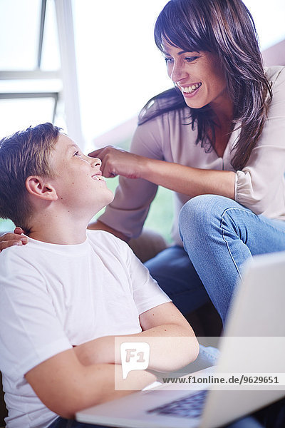 Mother and son at home using laptop