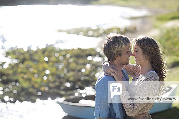Junges Paar umarmt am Seeufer