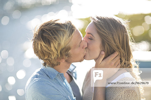 Young couple kissing at lakeshore