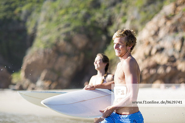 Junges Paar  das mit seinen Surfbrettern ins Meer rennt