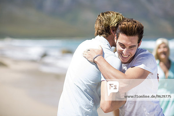 Freunde  die sich am Strand umarmen