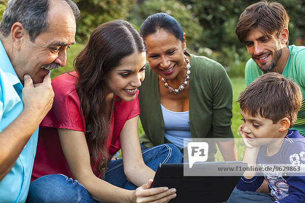 Drei Generationen Familie mit digitalem Tablett im Garten