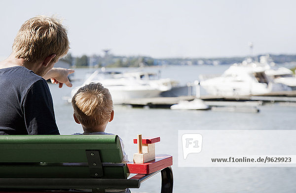 Rückansicht des männlichen Kleinkindes und des Vaters beim Beobachten von Booten im Hafen  Somerniemi  Finnland