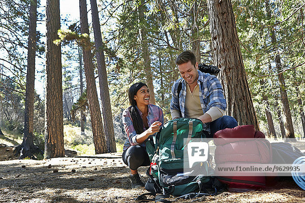 Young couple unpacking camping rucksack in forest  Los Angeles  California  USA