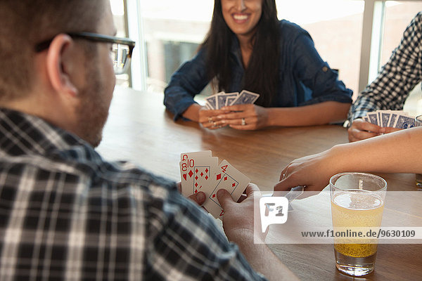 Gruppe von Freunden beim Kartenspielen am Tisch