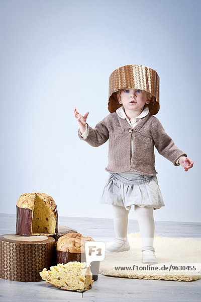 Porträt eines weiblichen Kleinkindes mit Pannetonkuchen-Etui als Hut