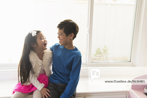 Bruder und Schwester auf dem Fensterplatz sitzend