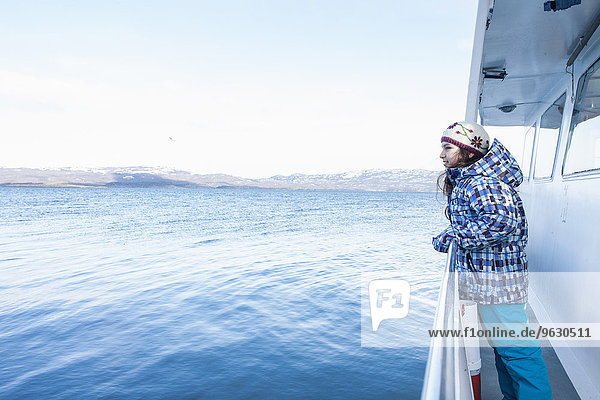 Mädchen lehnt sich gegen das Geländer auf einem Boot  das Richtung Küste segelt  Ushuaia  Feuerland  Argentinien