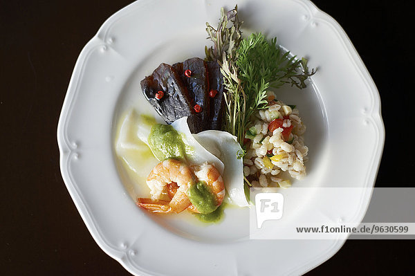 Plate with seafood variety and barley with sliced vegetable and herbs