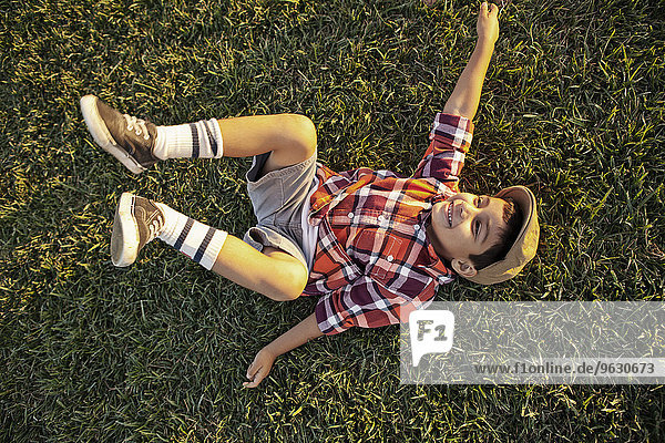 Junge auf Rasen liegend spielend