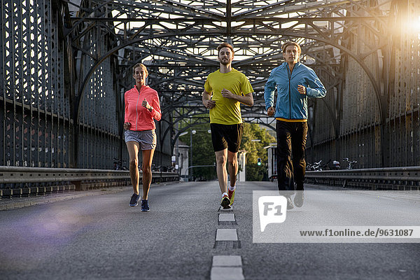 Friends jogging on bridge  Munich  Bavaria  Germany