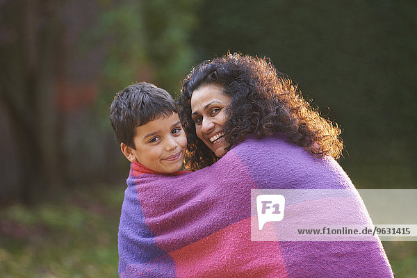 Mutter und Sohn im Garten in Decke gehüllt