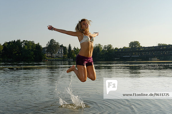 Partially dressed mid adult woman  jumping in lake