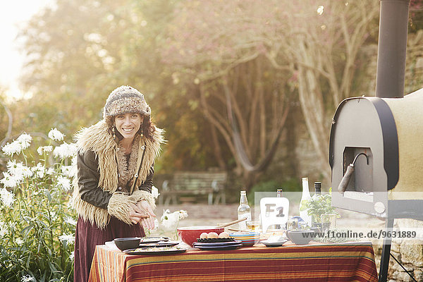 Reife Hippie-Frau beim Zubereiten von Essen auf dem Gartentisch