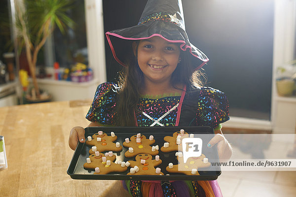 Mädchen in Halloween Hexenkostüm hält Tablett mit Lebkuchen Männer