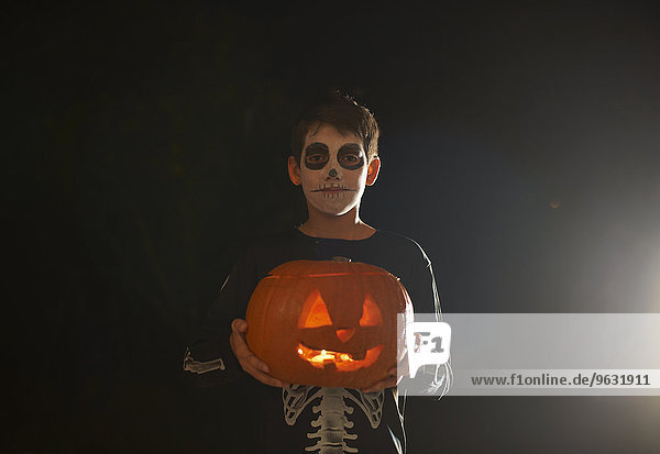 Porträt eines Jungen mit Halloween Skelett Kostüm mit Kürbis