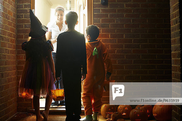 Rückansicht von drei Kindern  die Halloween-Kostüme tragen.