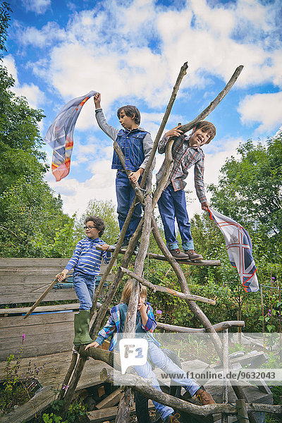 Vier Jungen klettern auf hausgemachtem Klettergerüst im Garten