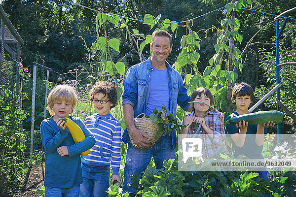 Zwei Männer und Söhne halten Gemüse auf Kleingarten.