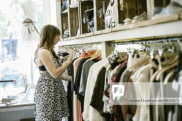 Mittlere erwachsene Frau sucht Kleiderstange in Vintage-Boutique