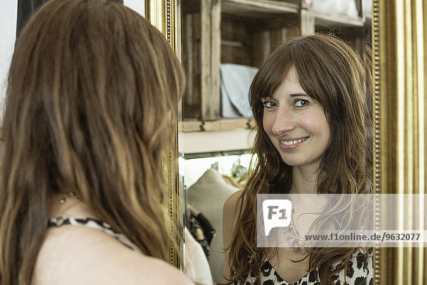 Reflected portrait of mid adult woman in boutique